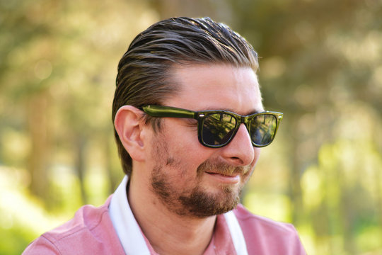 Young man's outdoors portrait looking at the camera who has sunglasses with natural green background. Neutral, happy, sad, disgust, fear, surprise Facial Emotion.