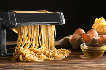 Metal pasta maker with dough and products on kitchen table