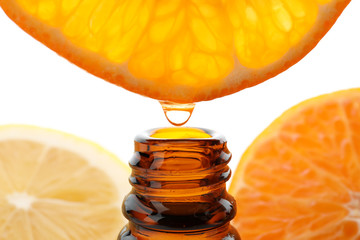 Dripping citrus essential oil into bottle on white background