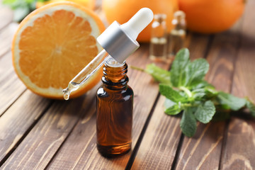 Bottle and dropper with citrus essential oil on wooden table