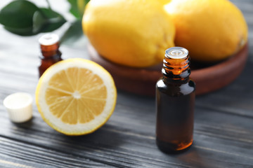 Bottle with citrus essential oil and fruit on wooden table