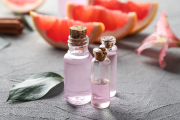Bottles with citrus essential oil on grey background