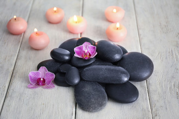 Fototapeta na wymiar Spa stones, flowers and burning candles on wooden background
