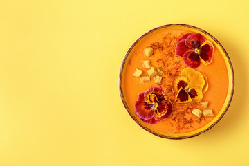 Pumpkin / carrot soup with saffron and edible flowers pansy.