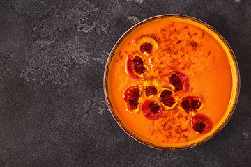 Smoothie or pumpkin / carrot soup with saffron and edible petals pansy flowers.