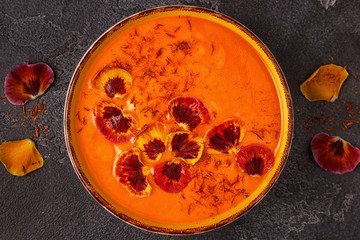 Smoothie or pumpkin / carrot soup with saffron and edible petals pansy flowers.