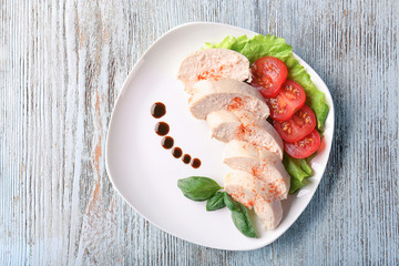 Plate with boiled chicken fillet and garnish on table