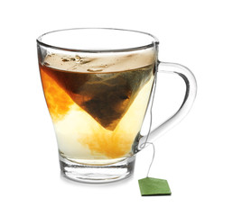 Brewing of hot tea in glass cup on white background