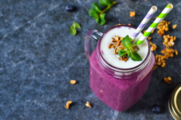 Detox drink - berry smoothie with yogurt, granola and honey on the stone, marble background