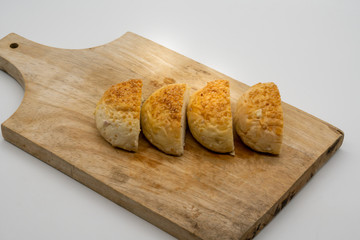 Homemade buns with sesame seeds on wooden square cutting board isolated on white