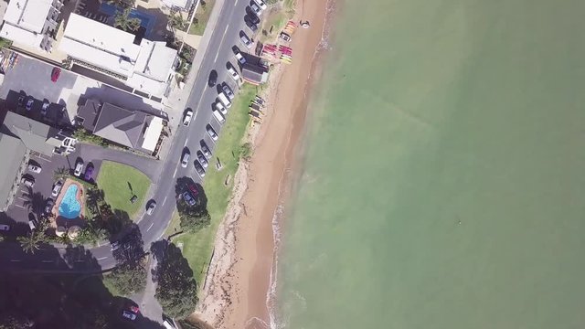 Aerial top down view, Paihia beach in New Zealands bay of islands. Fly over to see the road and ocean in early morning.