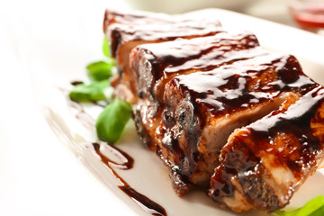Delicious grilled ribs with sauce on plate, closeup