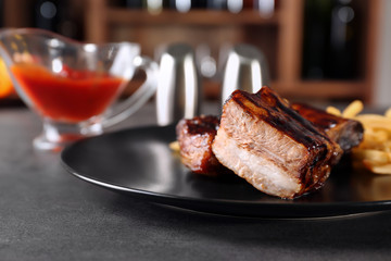 Plate with delicious grilled ribs on table