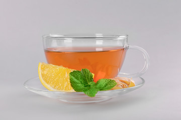 Cup of hot lemon tea with ginger on grey background