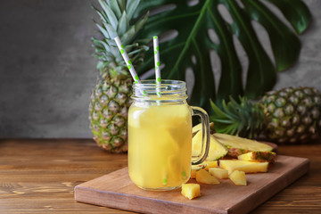 Mason jar with tasty fresh pineapple juice on wooden table