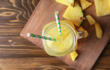 Mason jar with tasty fresh pineapple juice on wooden table