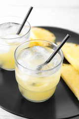 Glasses of tasty fresh pineapple juice on plate