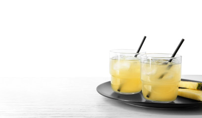 Fototapeta premium Plate with sliced pineapple and glasses of fresh juice on white table