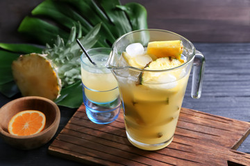 Glass jug with tasty fresh pineapple juice on table