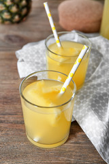 Glasses of tasty fresh pineapple juice on wooden table