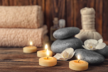 Fototapeta na wymiar Candles and spa stones for spa treatment on wooden table