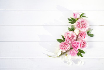 Obraz na płótnie Canvas Flower arrangement composition from pink flowers of roses on a white wooden background top view, flat lay, copy space.
