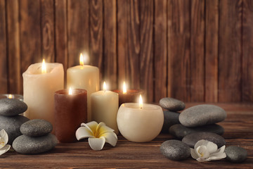 Obraz na płótnie Canvas Candles with spa stones on wooden background