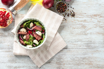 Tasty salad with meat and arugula in bowl on table