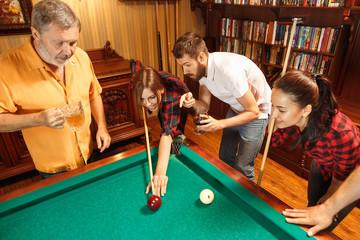 Fototapeta premium Young men and women playing billiards at office after work.