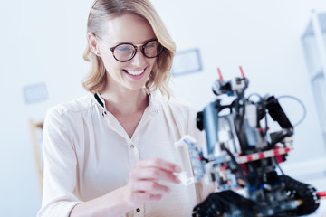 This is future. Cheerful nice smart woman smiling and looking at the robot while working on new technologies
