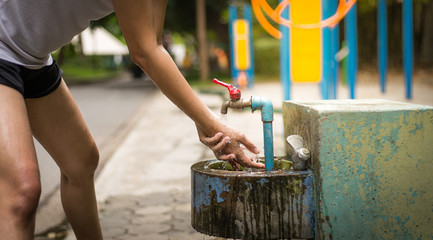 Woman washing hand with water from water tap in park