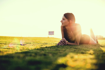 happy beautiful woman in bikini on the green grass on sunset.