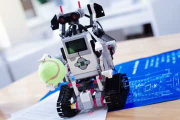Smart technology. Close up of a smart innovative robot standing on eh table and holding a tennis ball
