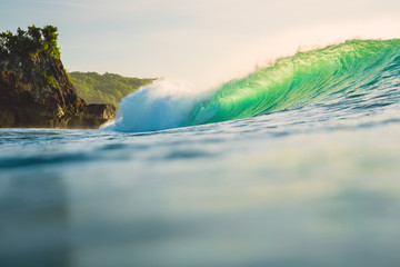 Crashing ocean wave. Breaking green barrel wave with sunset light