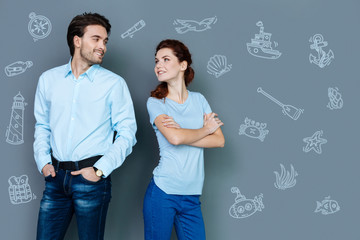 Cheerful couple. Positive young couple wearing similar clothes and looking at each other while thinking about travelling to the seaside
