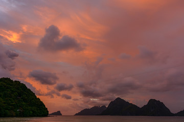 Meeting the sunset at sea. Las Cabanas beach - El Nido Philippines, Palawan. The sun sets in the sea. Tropical islands in the sea.