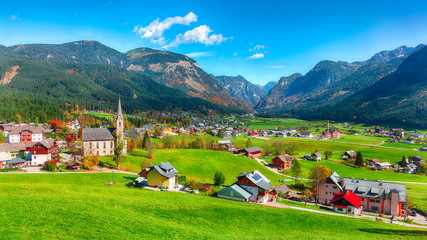Naklejka premium Alpine green fields and traditional wooden houses view of the Gosau village at autumn sunny day.