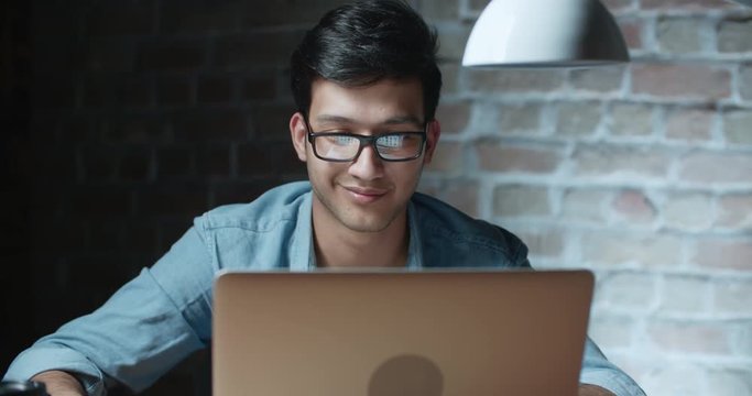 young handsome positive asian businessman working at laptop in loft office 4k dollyshot