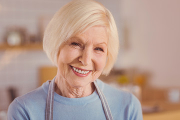 Happy barista. The close up of a cheerful elderly woman in an apron smiling at the camera brightly...