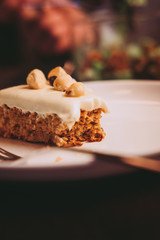 Raw vegan carrot cake with cashew cream layer from above on wooden table. Low key food photography styling concept. 