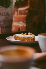 Raw vegan carrot cake with cashew cream layer from above on wooden table. Low key food photography styling concept. 