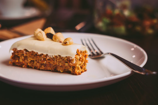Raw vegan carrot cake with cashew cream layer from above on wooden table. Low key food photography styling concept. 