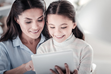 Playing together. Beautiful brunette female keeping smile on face while testing new gadget