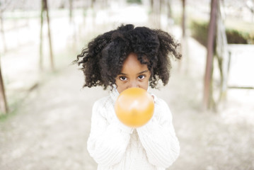 Girl blowing balloon outside