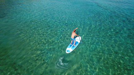 Aerial drone bird's eye view of paddle surfer in turquoise tropical clear waters