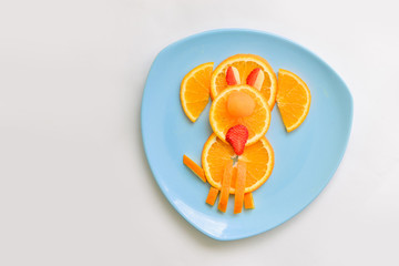 Fototapeta na wymiar A children's breakfast from an orange in the form of a dog. dessert for baby, animal on plate