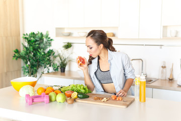 young beautiful girl cuts grapefruit to prepare fresh juice in the kitchen