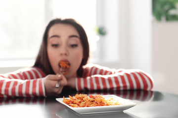 Young woman eating delicious pasta at table, closeup