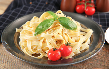 Plate of delicious pasta with cheese and tomatoes on table
