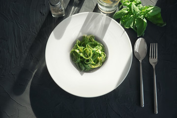 Plate of delicious pasta with pesto sauce on table, top view